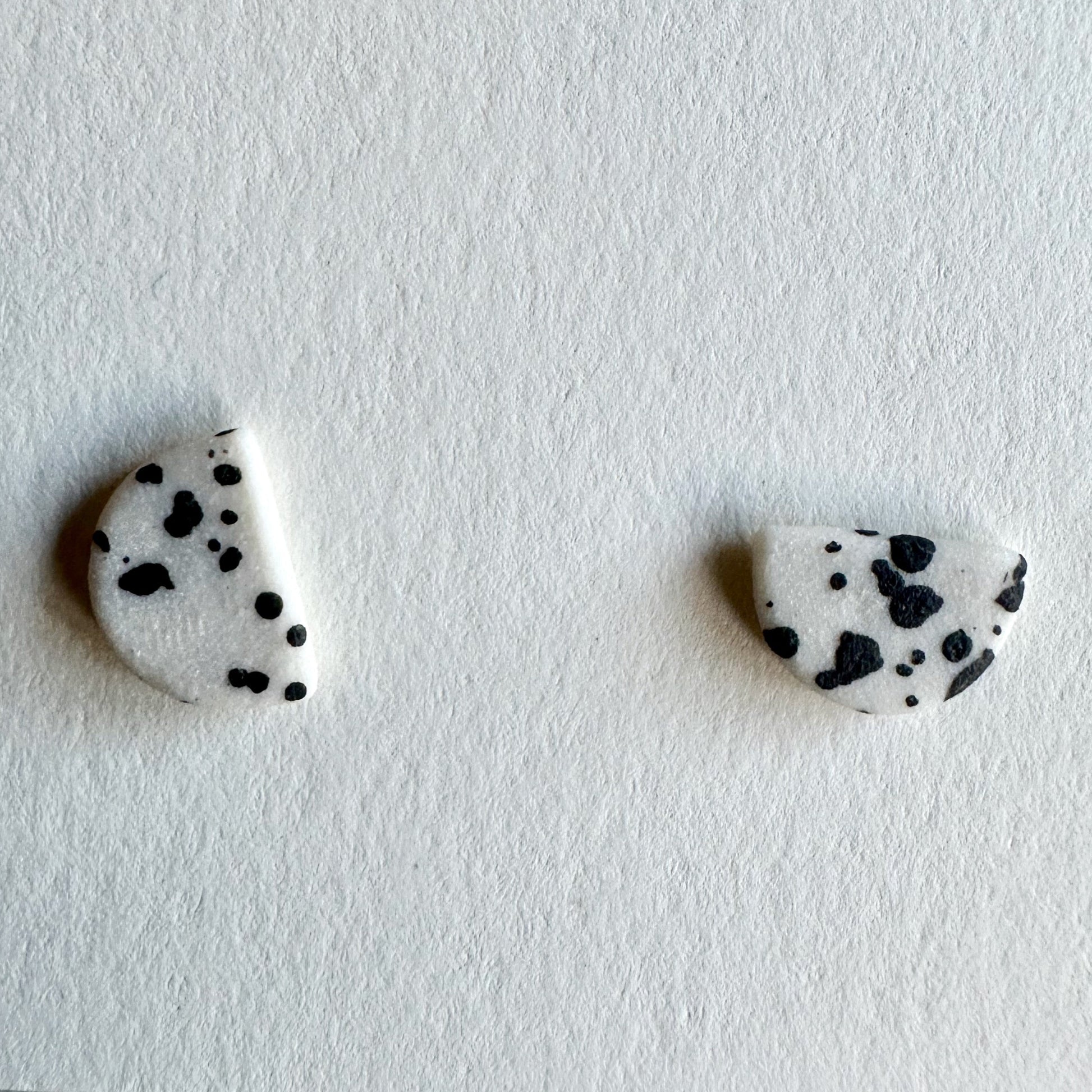 Pair of black and white patterned earrings on a light gray background